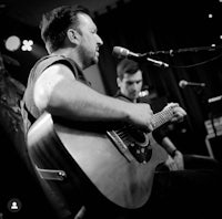 a man playing an acoustic guitar in front of a microphone